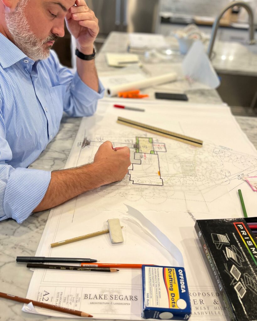 Blake Segars architect at desk working on hand-sketch, surrounding by pens and ruler