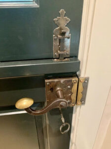 Ornate bronze door handle and lock on green door