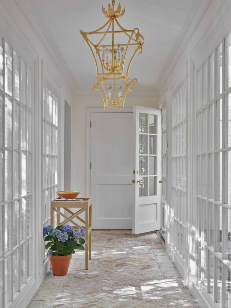a hallway with a chandelier and potted plant