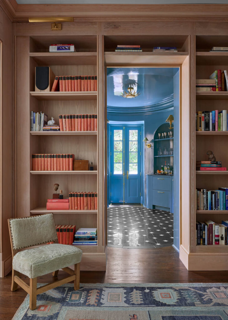 Books stacked on bookshelves with a reading chair on a rug