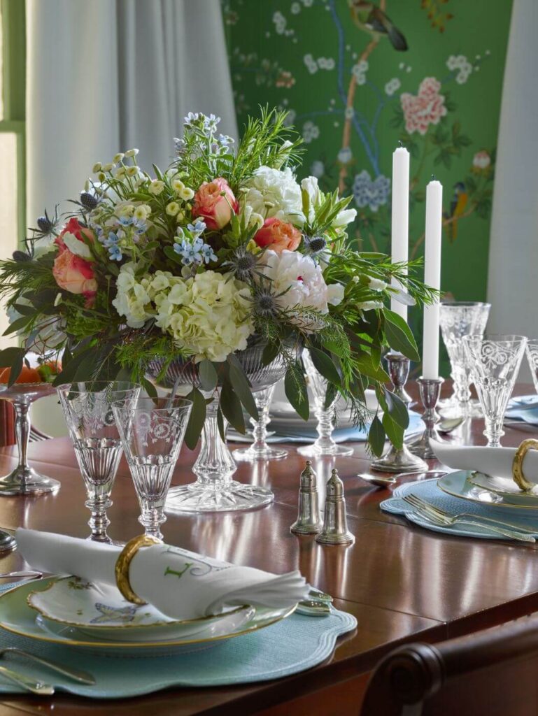 Vase of flowers on a dining table laid with silverware and plates