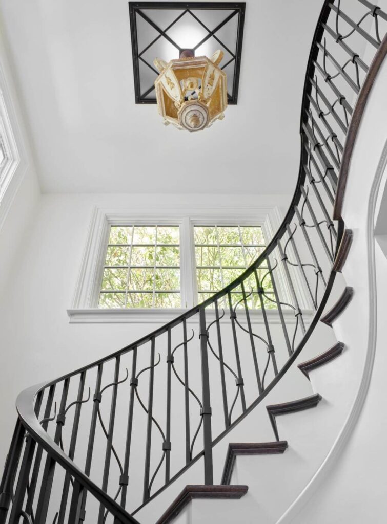 View up a staircase with chandelier on ceiling by Atlanta home architect